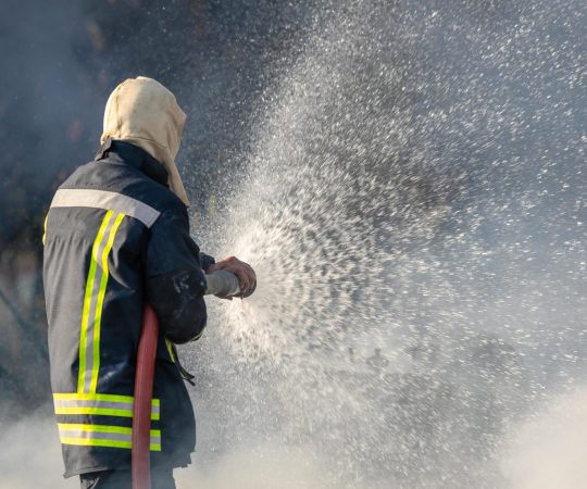 firefighter-spraying-water-from-big-water-hose-to-prevent-fire-free-photo