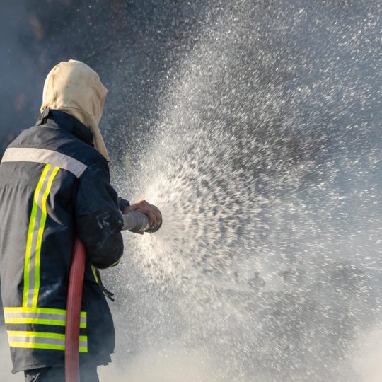 firefighter-spraying-water-from-big-water-hose-to-prevent-fire-free-photo
